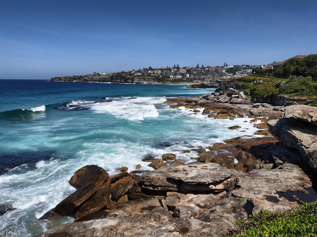 An der Steinküste bei Coogee wird das Wasser durch die starken Wellen aufgeschäumt.